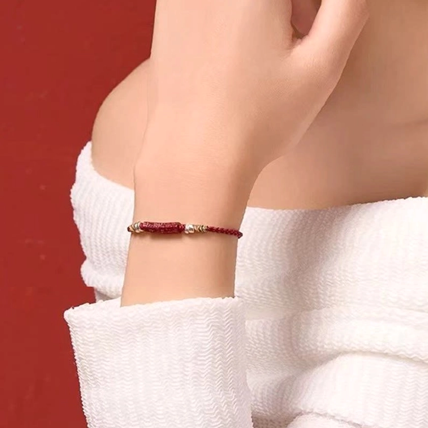 Red string prayer bracelet with colorful woven accents and silver decorative elements on terracotta background