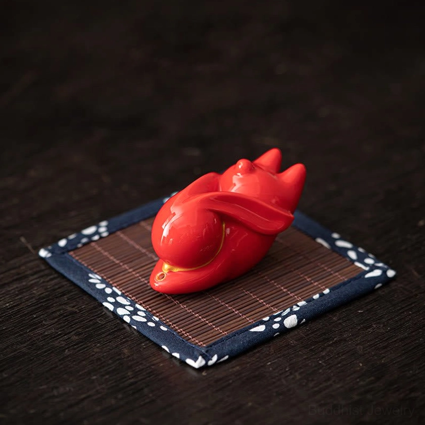 Red rabbit ceramic incense burner with bamboo mat on dark wooden tea desk for meditation