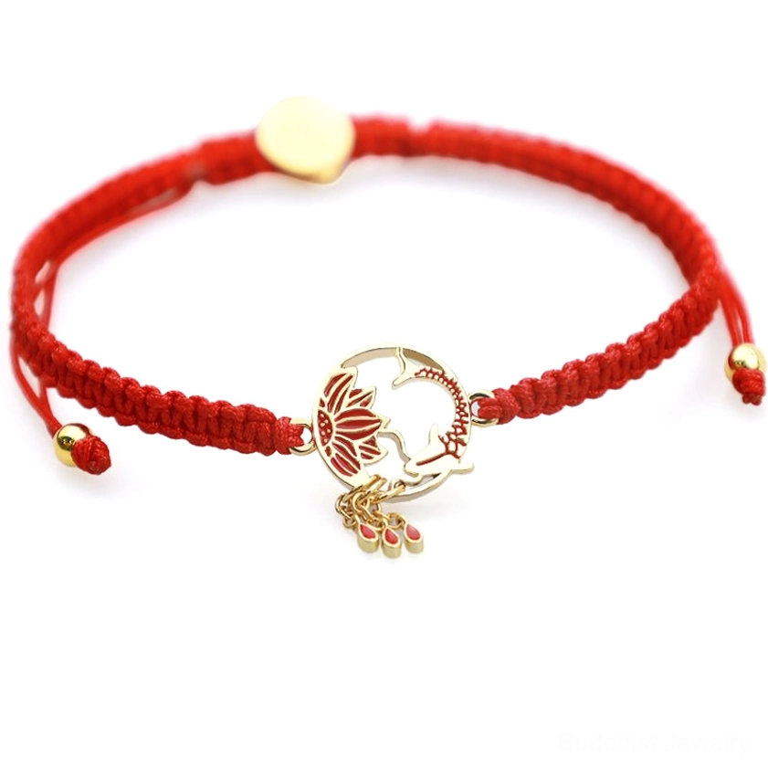 Red rope lucky bracelet with dual sliding adjustment beads, enameled charm, and red drop pendants, flat lay