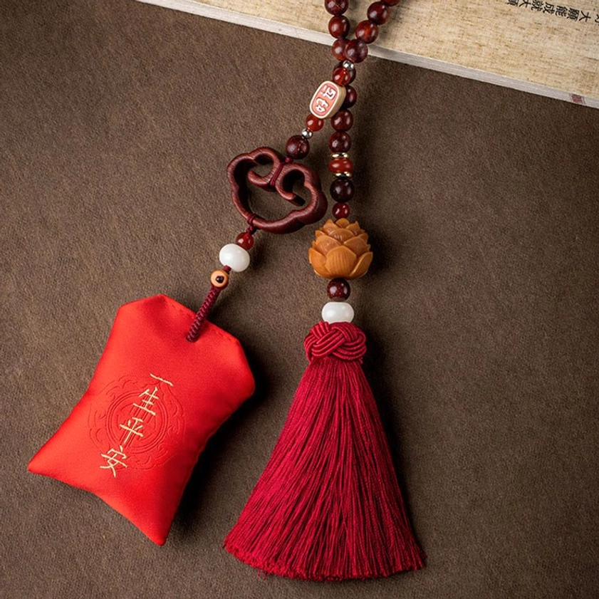 Red sachet hanging ornament with life-long peace embroidery, wooden cloud charm, and red tassel on neutral background