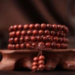 108 bead red sandalwood Buddhist prayer mala bracelet with guru bead and tassel on wooden display stand