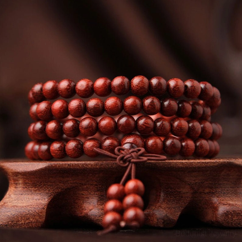 108 bead red sandalwood Buddhist prayer mala bracelet with guru bead and tassel on wooden display stand