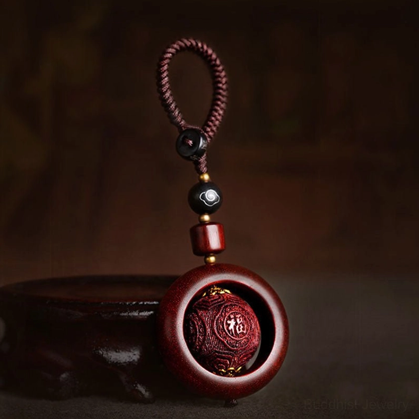 Red sandalwood and ebony prayer keychain with blessing carved design and braided rope attachment