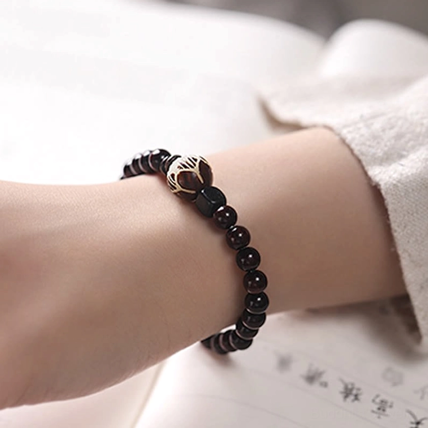 Meditation practice with red sandalwood bracelet worn during spiritual session, showing practical use for mindfulness and Buddhist practice