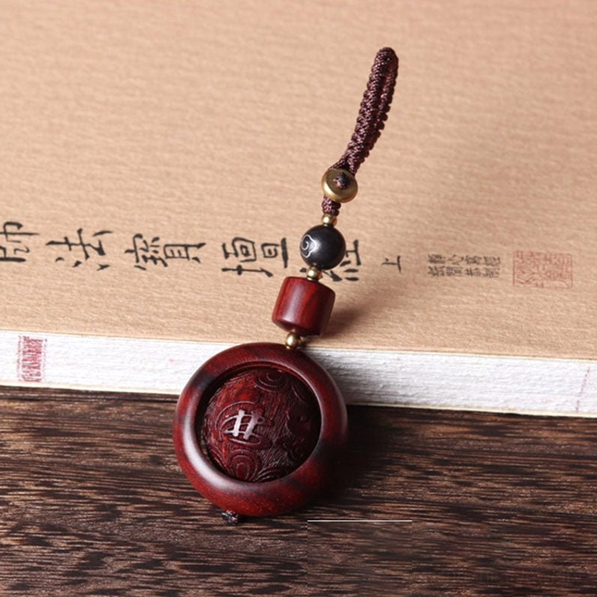 Red sandalwood prayer keychain featuring Buddha figure carving with sacred Buddhist symbolism