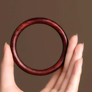 Red Sandalwood Buddhist Protection Bracelet held in palm - front close-up view showing reddish-brown polished wood grain