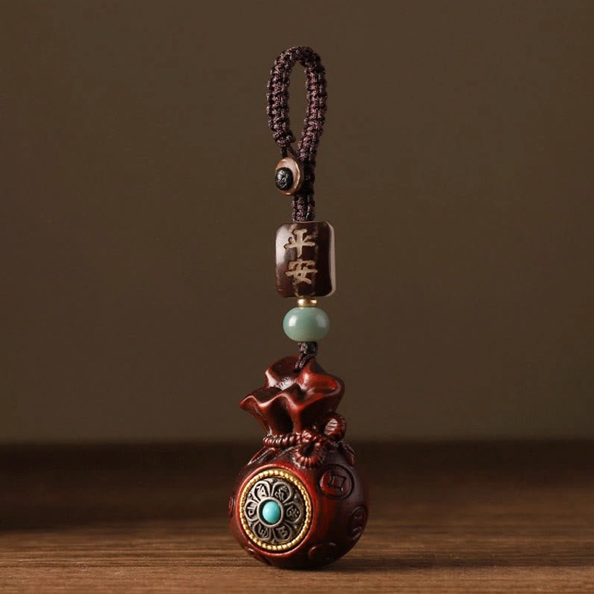 Red sandalwood Buddhist money bag charm showing carved money bag silhouette and rotatable turquoise-inlaid decoration detail