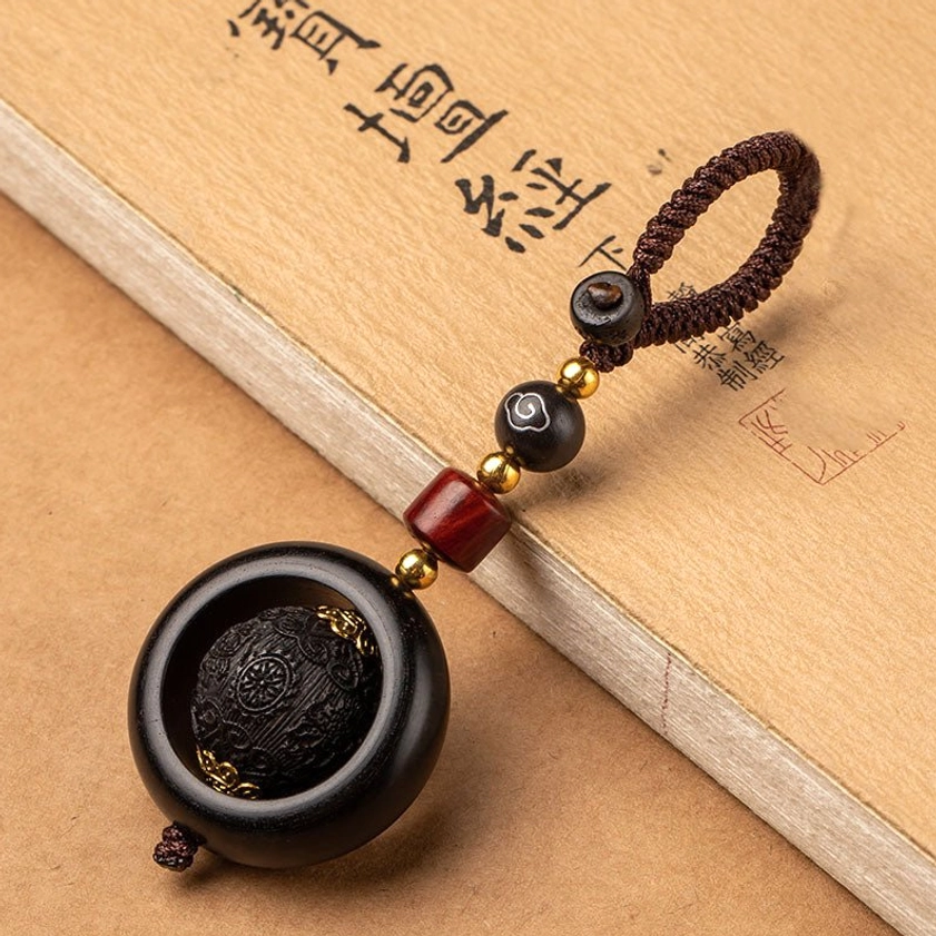 Red sandalwood and ebony prayer keychain featuring auspicious symbol carved with premium ebony wood details