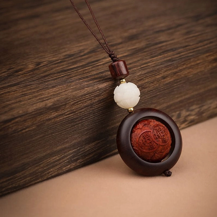 Red sandalwood rotating prayer keychain with fortune and lotus carving representing prosperity and spiritual transformation