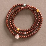 Red sandalwood Fu character protection bracelet with 925 sterling silver charm on brown background, top view