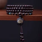 108 bead red sandalwood mala bracelet with square lotus pendant and wooden tassel, top-down studio display