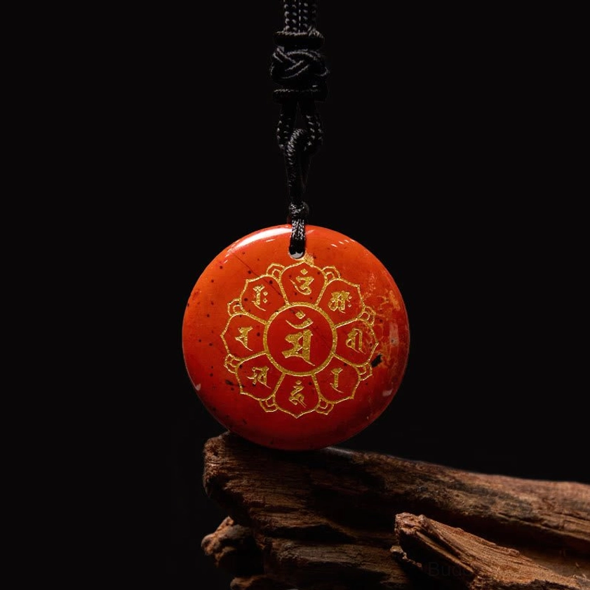 Red Stone Om Mani Padme Hum Buddhist pendant with gold Sanskrit engraving on wooden texture background