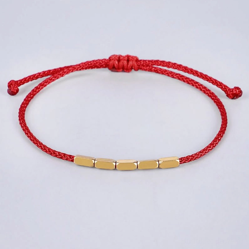 Red woven cord Buddhist bracelet with cylindrical copper beads and adjustable knot design, close-up front view