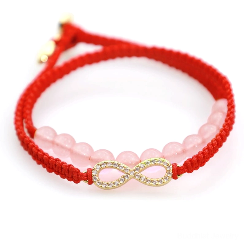 Red string Buddhist protection bracelet side angle with diamond-inlaid infinity charm and pink crystal beads on white background