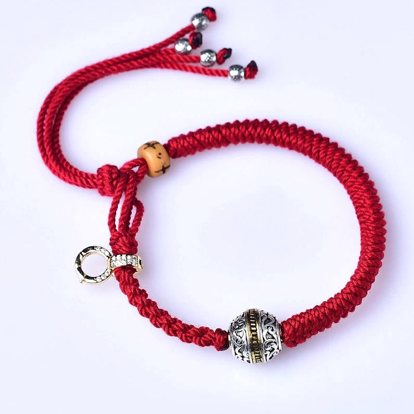 Red braided Buddhist string bracelet with engraved metal bead and crystal clasp, white background product view