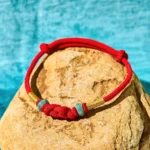 Red string jade couple bracelet top view with gold accents and braided knot design