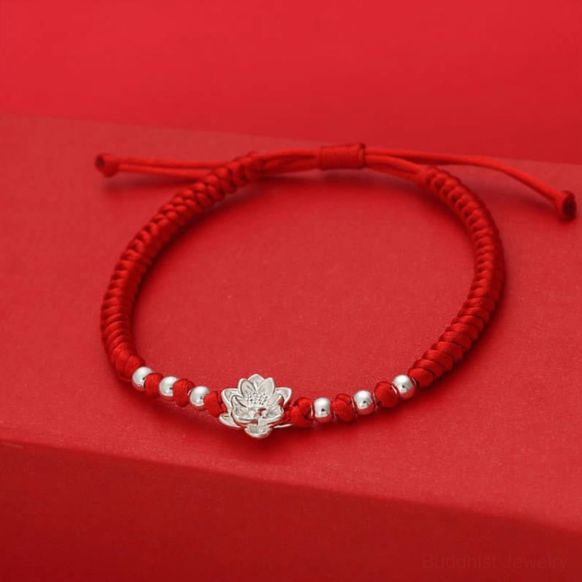 Red string luck bracelet overhead view showing adjustable knot and silver lotus charm placement