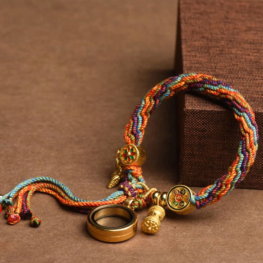 Rainbow braided Buddhist lucky bracelet with gold metal charms and ring pendant on wooden box