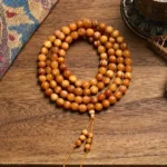 108 resin-rich pine wood mala beads with guru bead and tassel, overhead view on ethnic tapestry background