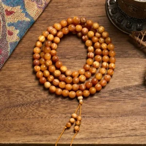 108 resin-rich pine wood mala beads with guru bead and tassel, overhead view on ethnic tapestry background
