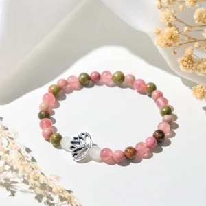 Rhodonite unakite lotus healing bracelet flat lay with silver lotus charm on white fabric and dried flowers