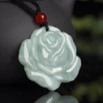 Carved rose jade pendant necklace with red agate bead on black cord, shown in side close-up with celadon jade detail