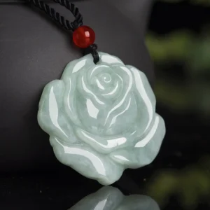 Carved rose jade pendant necklace with red agate bead on black cord, shown in side close-up with celadon jade detail
