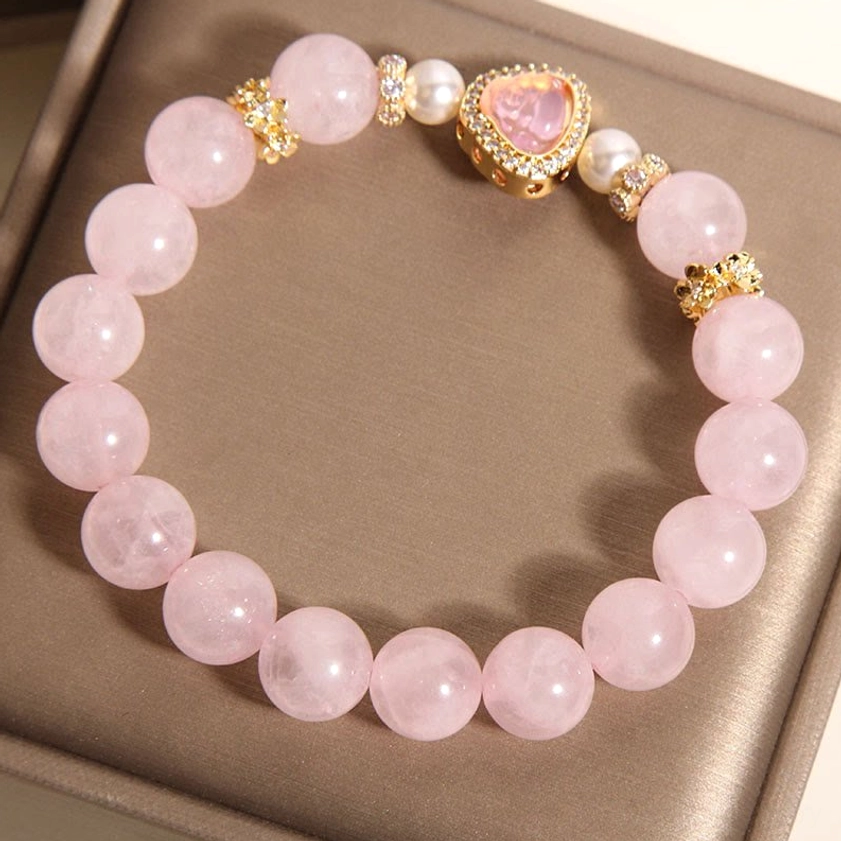 Rose quartz Buddha bracelet side overhead view inside open brown jewelry gift box with gold rhinestone bead spacers and soft pink crystal beads
