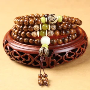Handcrafted rosewood Buddhist prayer mala bracelet with 108 beads, Bodhi seeds, and tassel pendant displayed on carved wooden stand