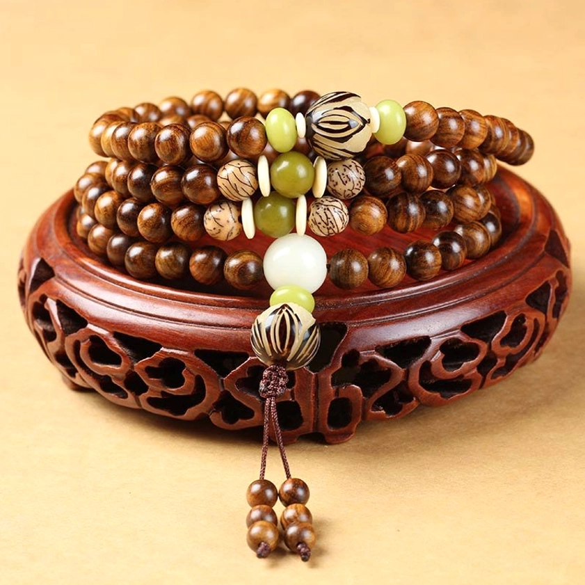 Handcrafted rosewood Buddhist prayer mala bracelet with 108 beads, Bodhi seeds, and tassel pendant displayed on carved wooden stand