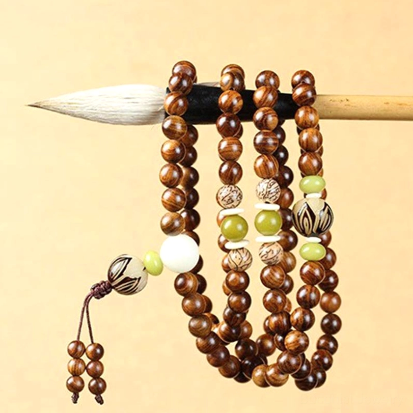 Long rosewood Buddhist mala necklace displayed on Chinese calligraphy brush, showing tassel pendant and mixed decorative beads