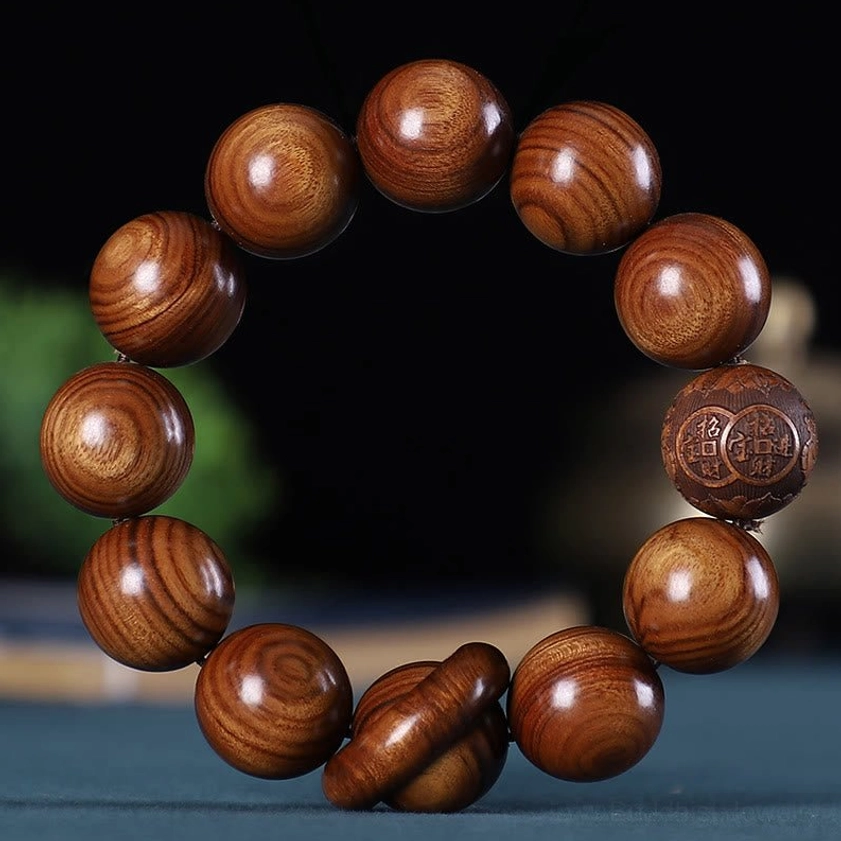 Plain rosewood Buddhist bracelet with smooth round beads, showing natural wood grain texture and one engraved coin bead for spiritual protection