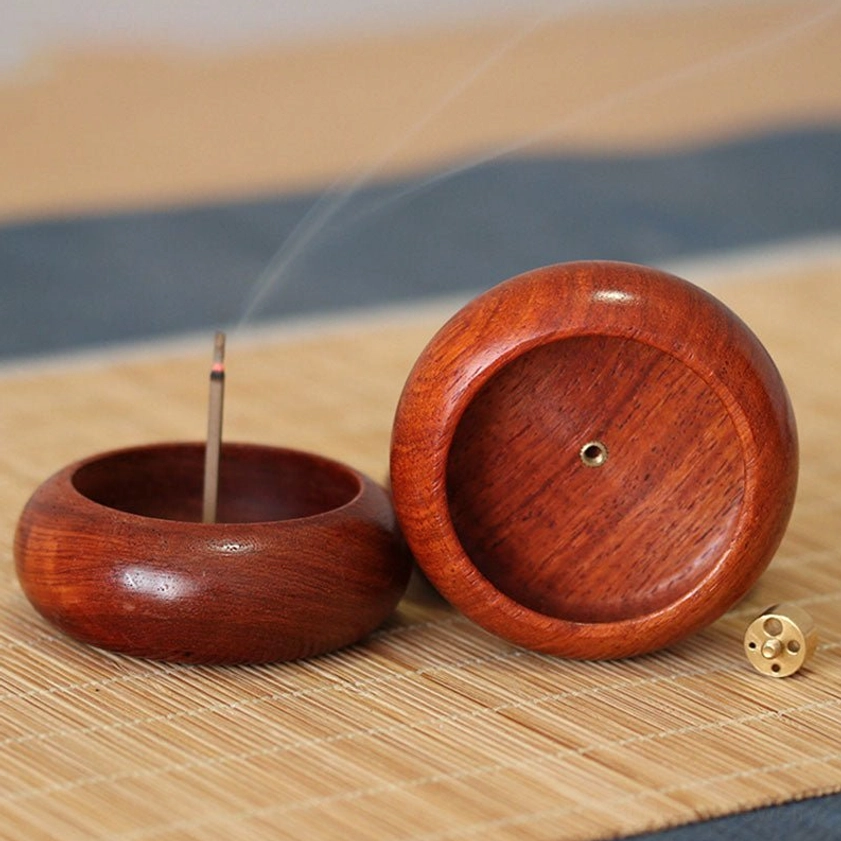 Handcrafted rosewood incense holder with loose brass insert and lit stick, front flat view on bamboo placemat