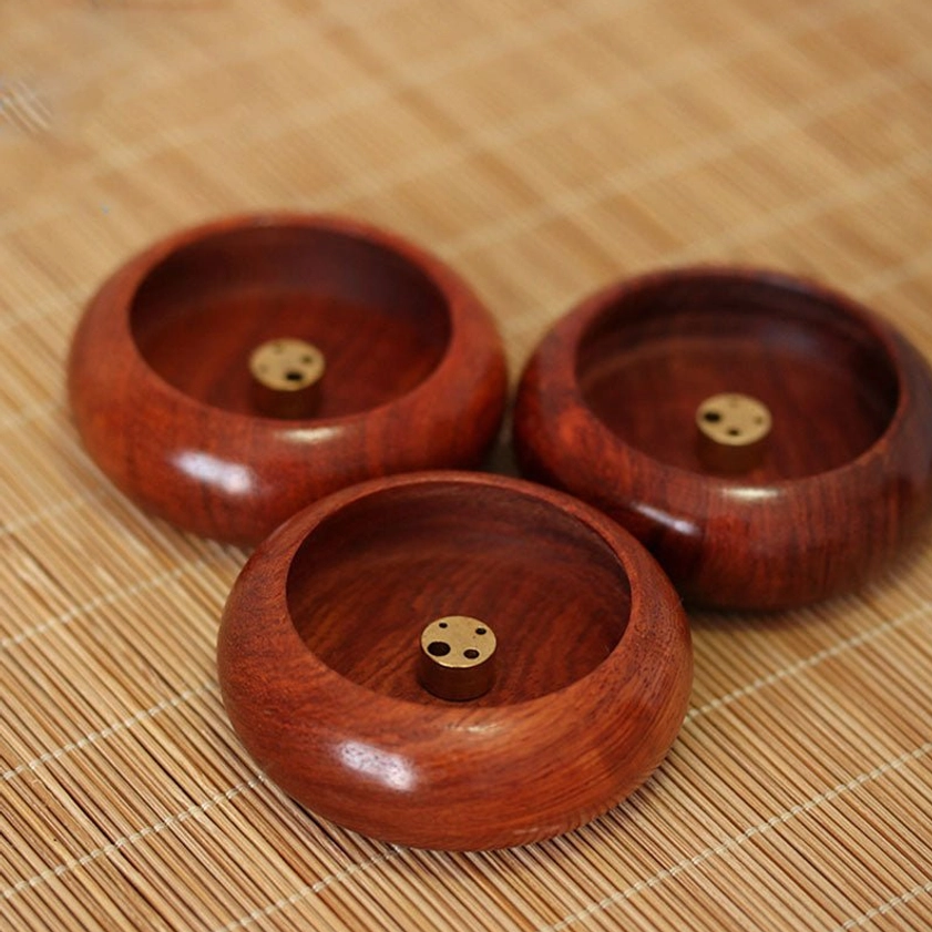 Set of three handcrafted rosewood incense holders with brass inserts, top-down view showing natural wood variation