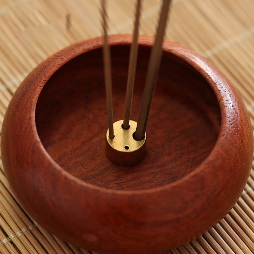 Rosewood incense burner with brass insert supporting three aromatic sticks, top-down perspective showing capacity and design