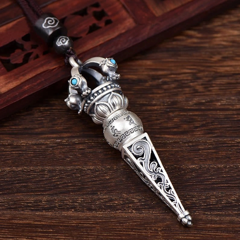 Buddhist mantra pendant necklace with black beaded cord showing intricate floral patterns and Dorje Vajra design from side view