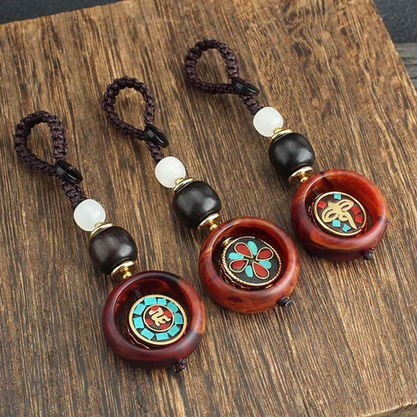 Detailed view of rotating Buddhist keychain charm showing sacred emblem design and natural ebony wood texture