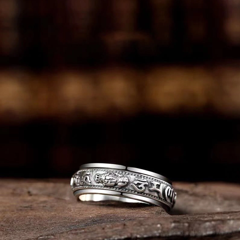 Side close-up of embossed rotating buddhist ring showing double-layered rotating band with detailed engraved carvings in vintage silver