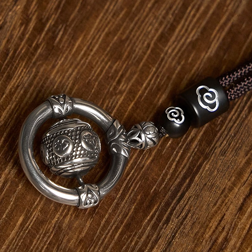 Close-up side view of rotating copper Buddhist pendant necklace showing circular metal frame and carved rotatable bead detail