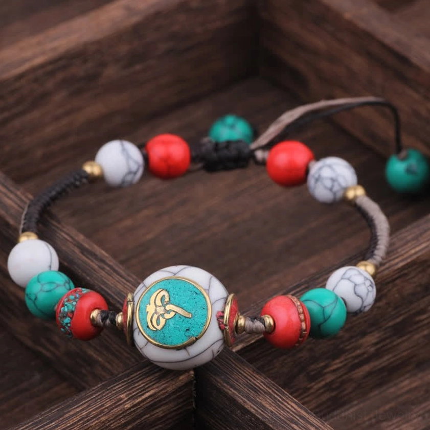 Round turquoise black white rope Buddhist bracelet with round central bead and colorful braided cord closeup