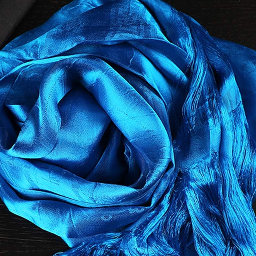 Royal blue sacred khata blessing scarf with subtle jacquard details and glossy satin texture, fully rolled overhead view