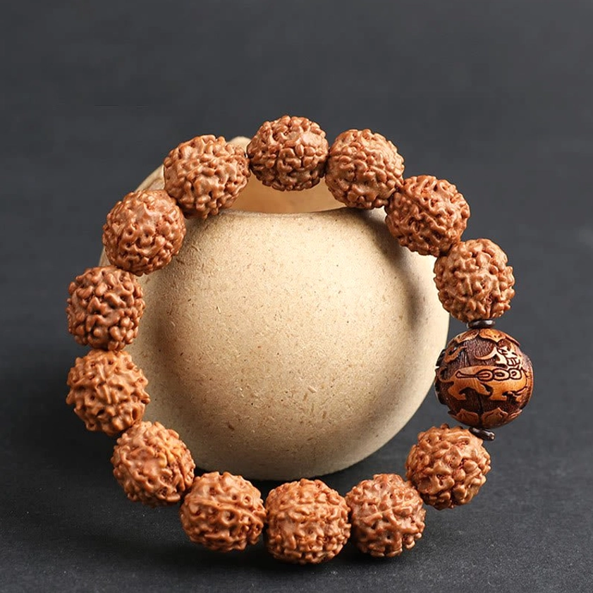 Rudraksha Bodhi seed bracelet top-down view dark grey background textured brown beads ornate wooden accent