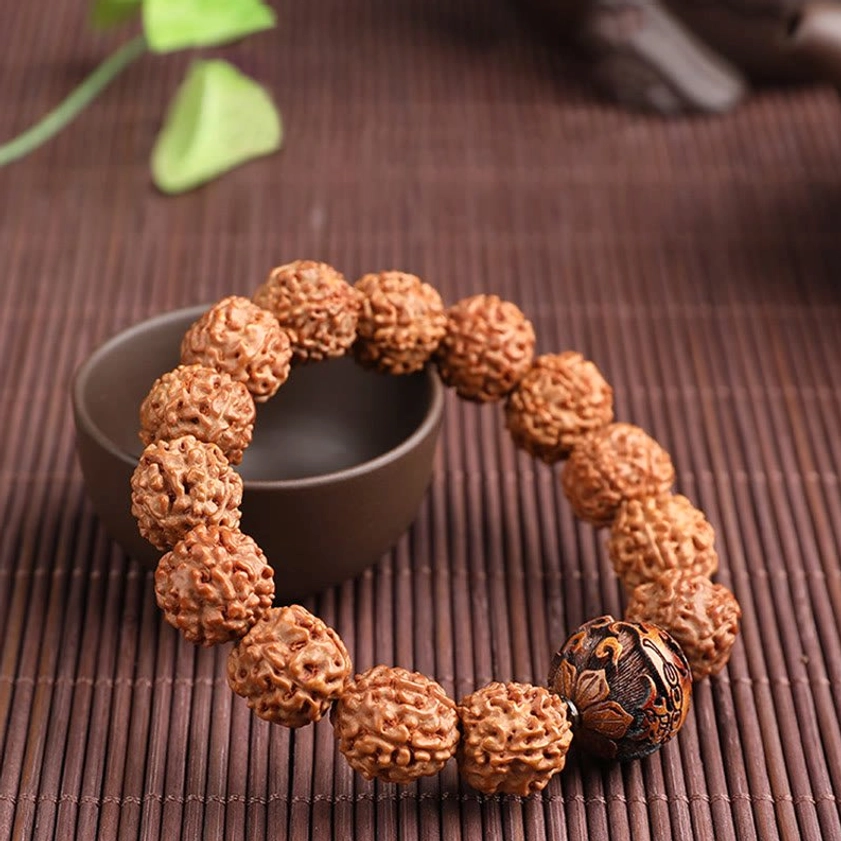 Handcrafted Rudraksha Bodhi bracelet flat lay on bamboo mat with ceramic bowl earthy brown beads feng shui Pixiu accent