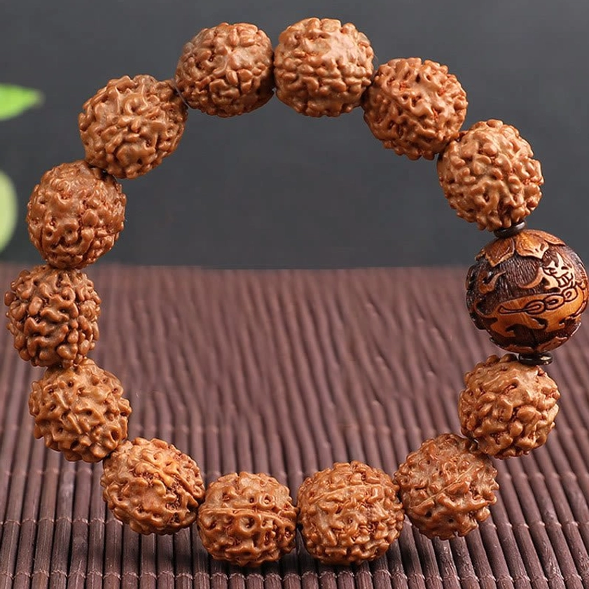 Single strand Rudraksha Bodhi Pixiu bracelet flat lay on bamboo mat uniform brown beads carved wooden focal bead