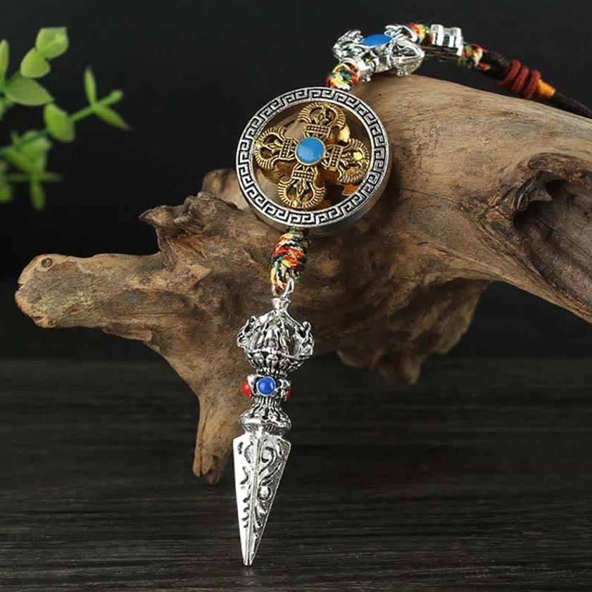 Side view of Buddhist car hanging with braided rope, dharma wheel pendant, and traditional phurba charm