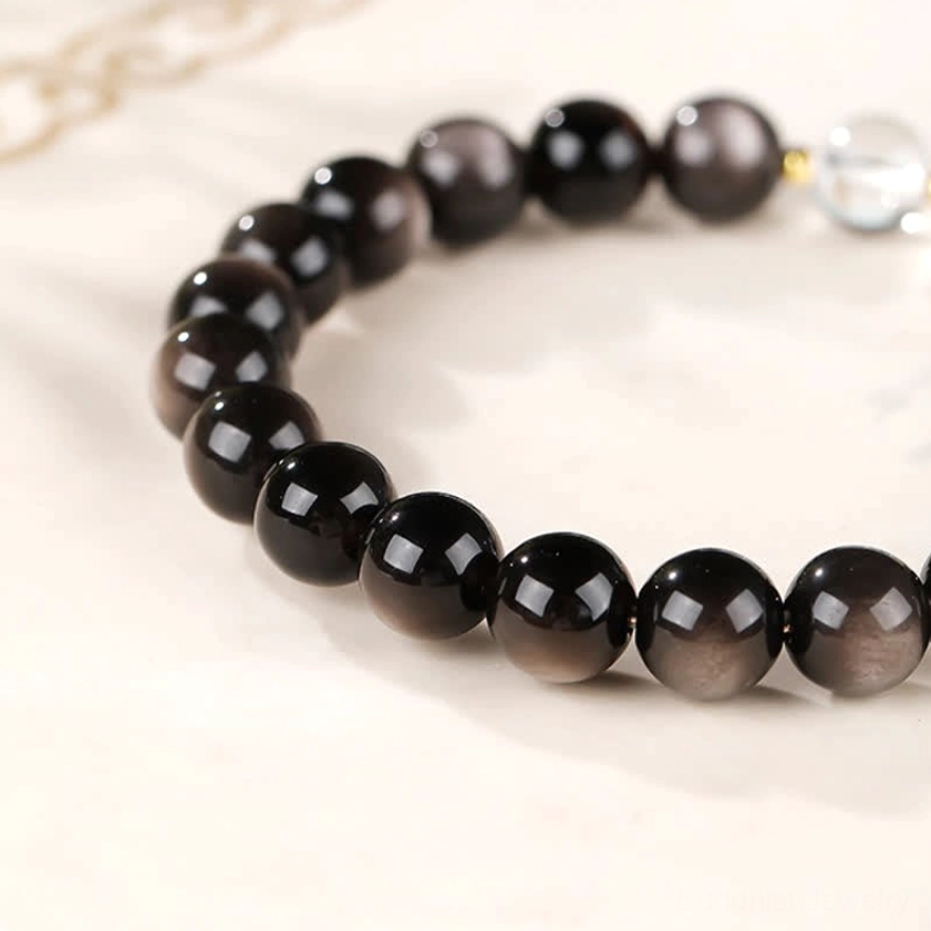 Black silver sheen obsidian Buddhist bracelet with sacred Dzi bead, demonstrating protective amulet properties and craftsmanship