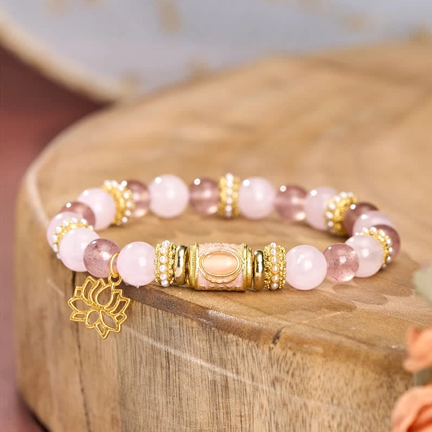 Rose quartz strawberry quartz bracelet on wooden stand featuring symmetrical bead layout and lotus charm