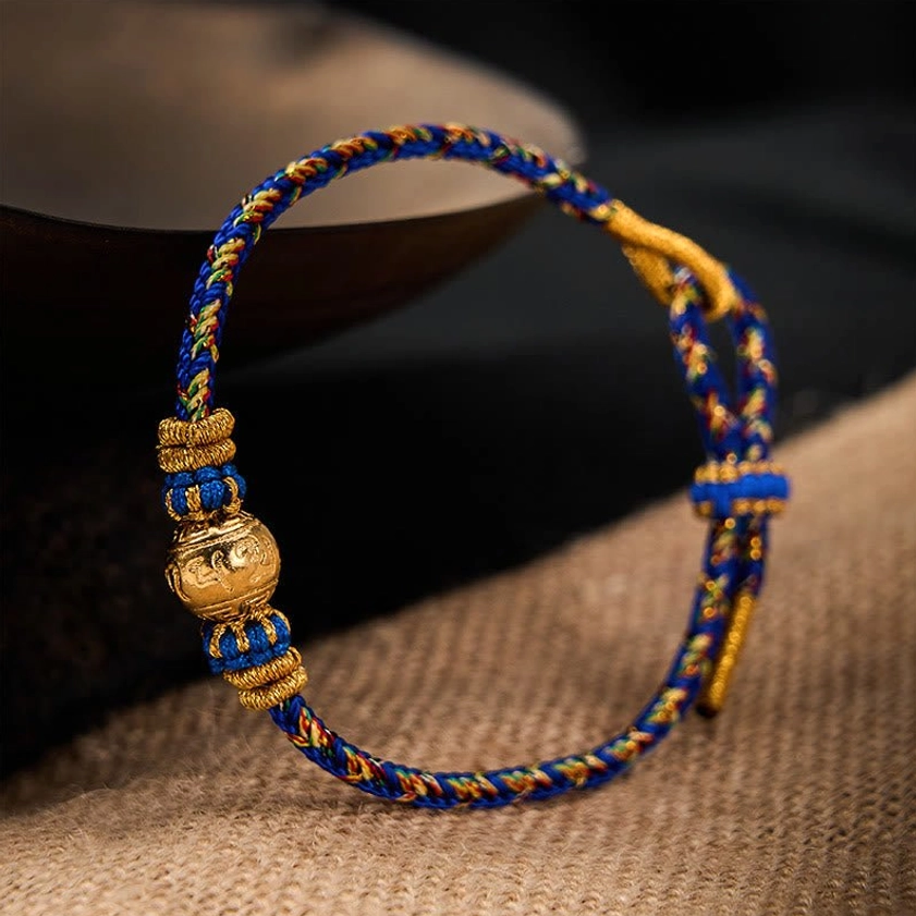 Sacred Om Mani Padme Hum bracelet featuring blue-gold braid and decorative knots with metal mantra bead