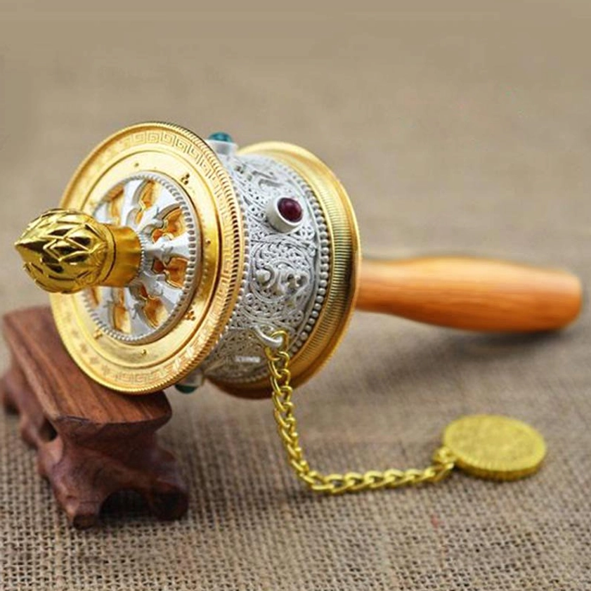 Silver-gold carved Buddhist prayer wheel with semi-precious stone inlays and decorative hanging chain, artisanal craftsmanship detail