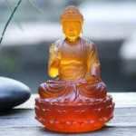 Sakyamuni Buddha Liuli crystal statue front three-quarter view showing lotus throne, monk robes, and vitarka mudra hand gesture on wooden table